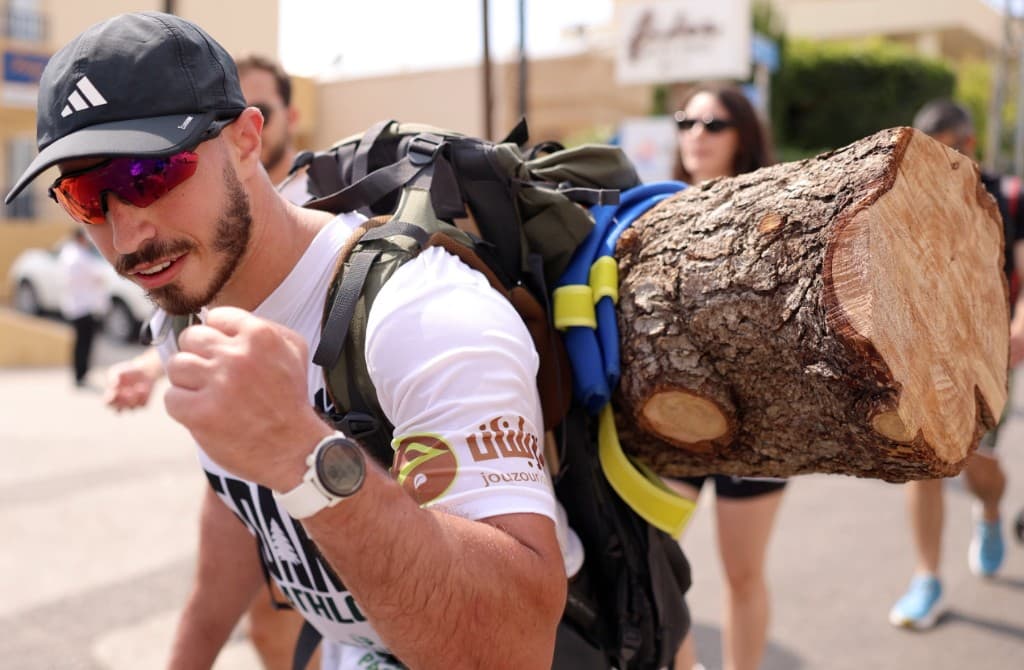 Joe Hachem carrying a cedar log, founder of Project Athlete